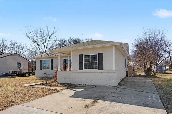 a front view of a house with a yard covered with snow and trees