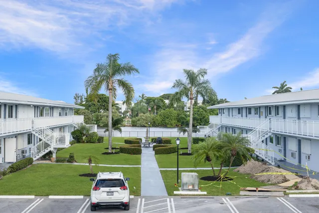 a view of a big house with a big yard and palm trees