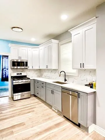 a kitchen with stainless steel appliances granite countertop a stove and white cabinets