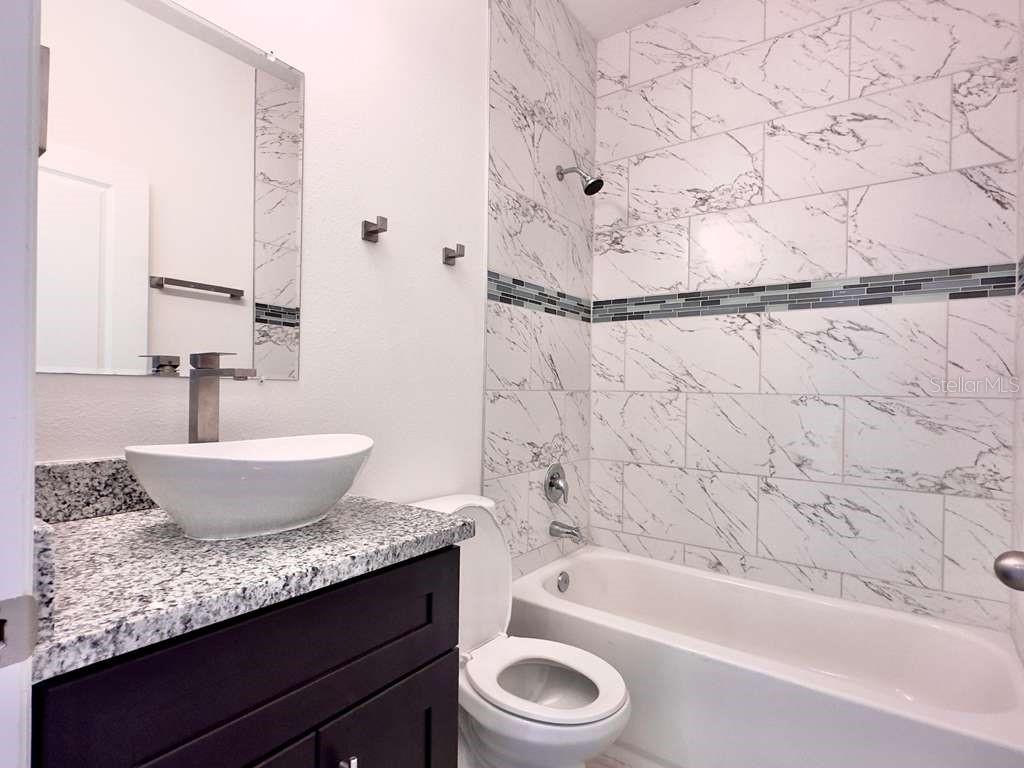 15885 Southwest 35th Court Road, Unit 2 Ocala, FL 34473 - Photo 11 of 21 a bathroom with a granite countertop sink a toilet and bathtub