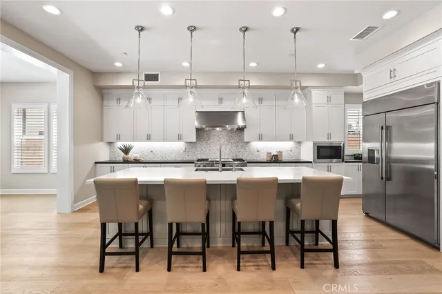 a dining room with stainless steel appliances kitchen island granite countertop a dining table chairs and a refrigerator