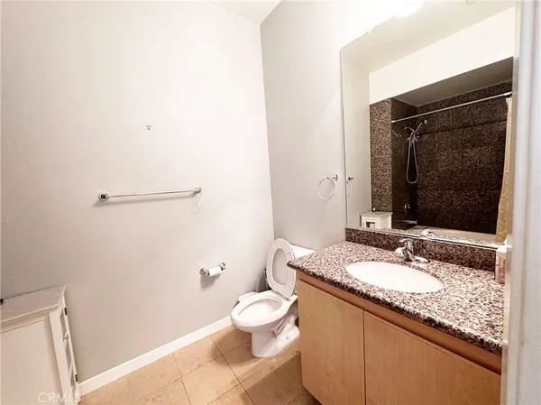 a bathroom with a granite countertop sink a toilet and a mirror