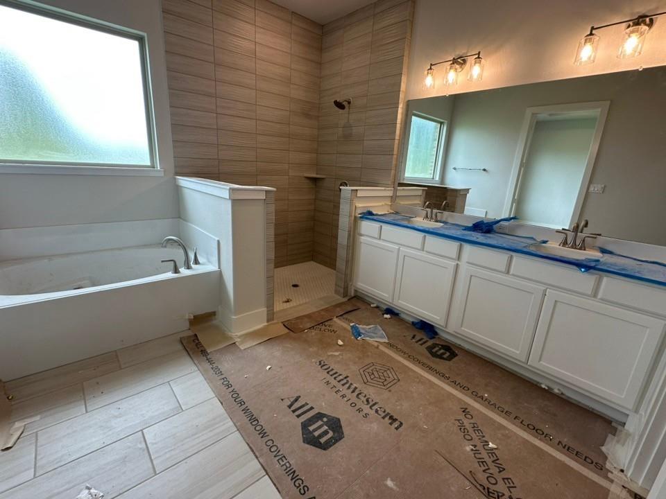 410 Cobb Road Leonard, TX 75452 - Photo 14 of 24 Bathroom featuring a dual vanity with white cabinetry, a built-in tub, and a shower with horizontal tile surround