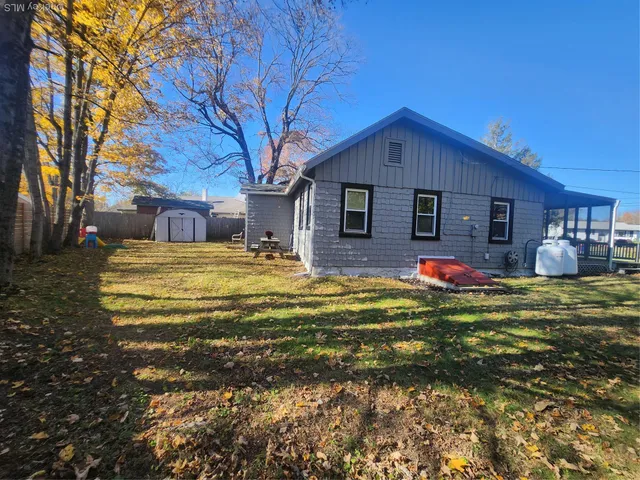 a front view of house with outdoor seating and covered with trees