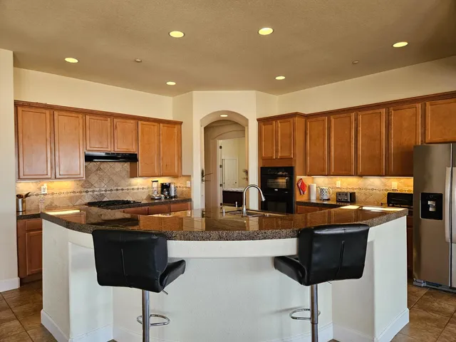 a kitchen with stainless steel appliances granite countertop a refrigerator and a stove