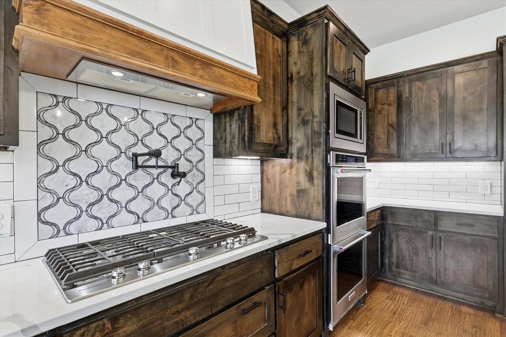 120 Grace Vw Road Weatherford, TX 76088 - Photo 13 of 40 Kitchen featuring a gas range cooktop with a pot filler, stainless steel appliances, dark wood cabinetry, white countertops, and subway tile backsplash with a decorative accent panel