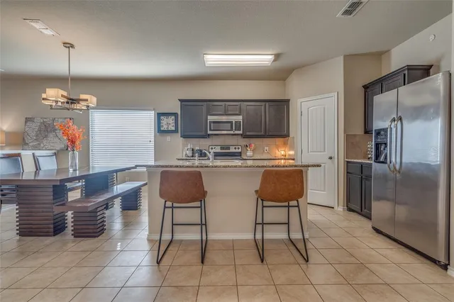 a kitchen with kitchen island a stove a table and chairs in it
