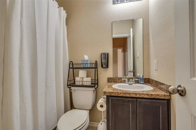 a bathroom with a granite countertop sink vanity mirror and toilet