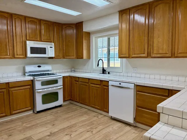 a kitchen with granite countertop stainless steel appliances wooden cabinets and a sink