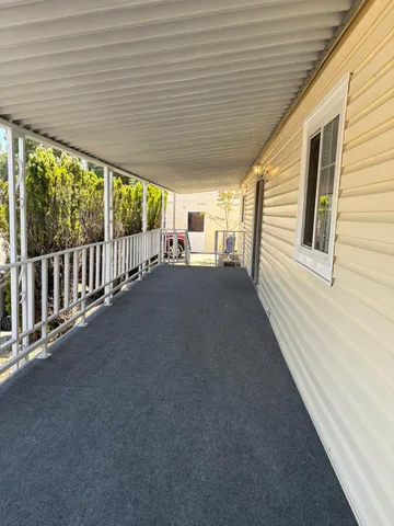 a view of a porch with wooden floor and roof with a garden view