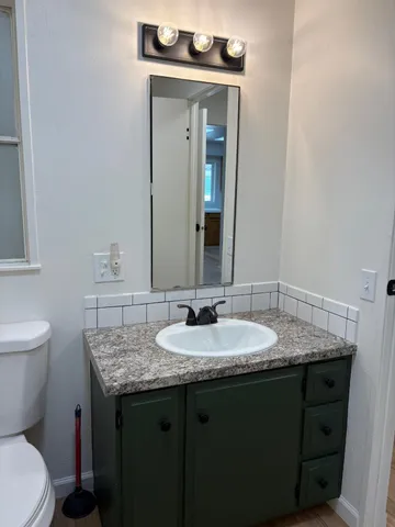 a bathroom with a granite countertop sink a toilet and mirror