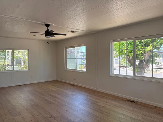 a view of an empty room with wooden floor and a window