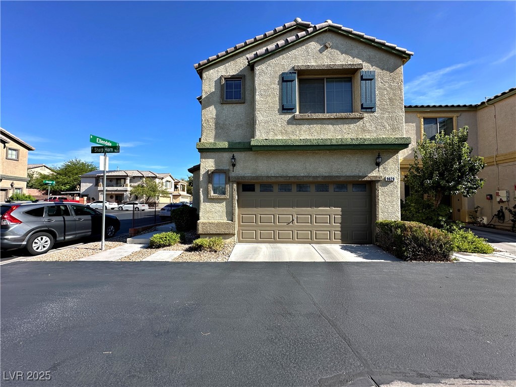 Mediterranean / spanish-style house with a garage, stucco siding, a residential view, and a tile roof