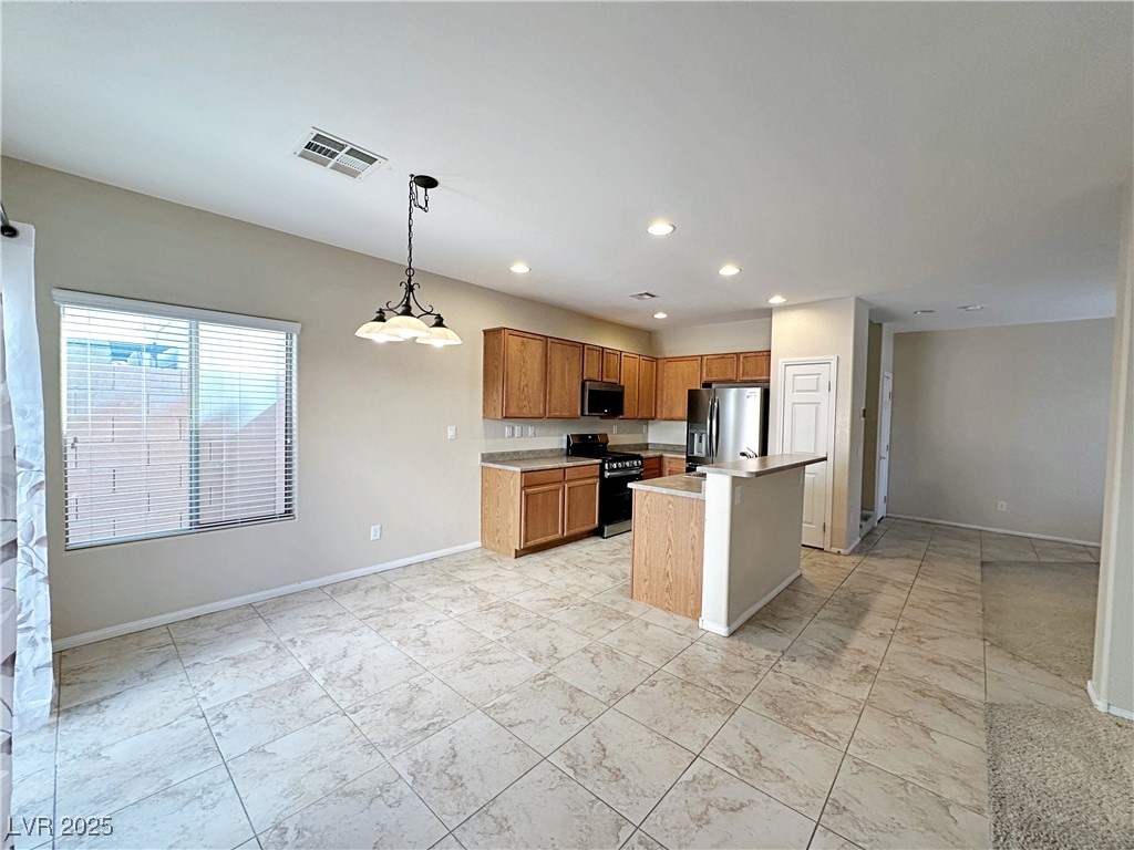 9620 Sharp Horn Court Las Vegas, NV 89149 - Photo 10 of 40 Kitchen with a kitchen island, light countertops, appliances with stainless steel finishes, pendant lighting, and brown cabinetry