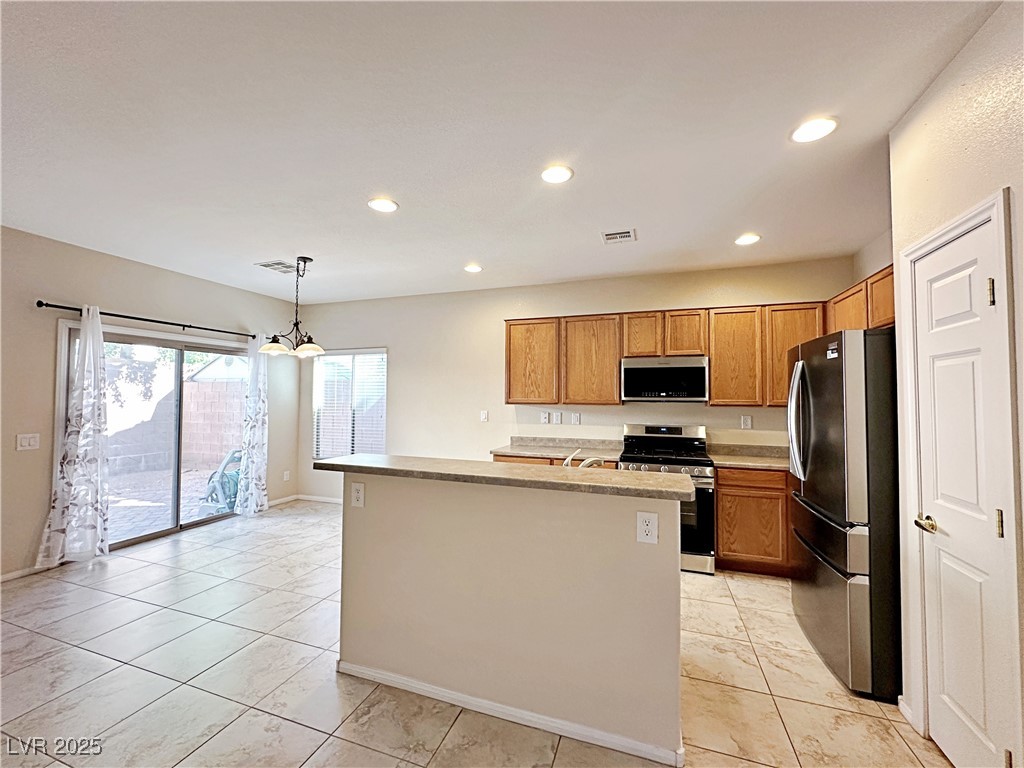 9620 Sharp Horn Court Las Vegas, NV 89149 - Photo 14 of 40 Kitchen with stainless steel appliances, light countertops, recessed lighting, hanging light fixtures, and a center island with sink