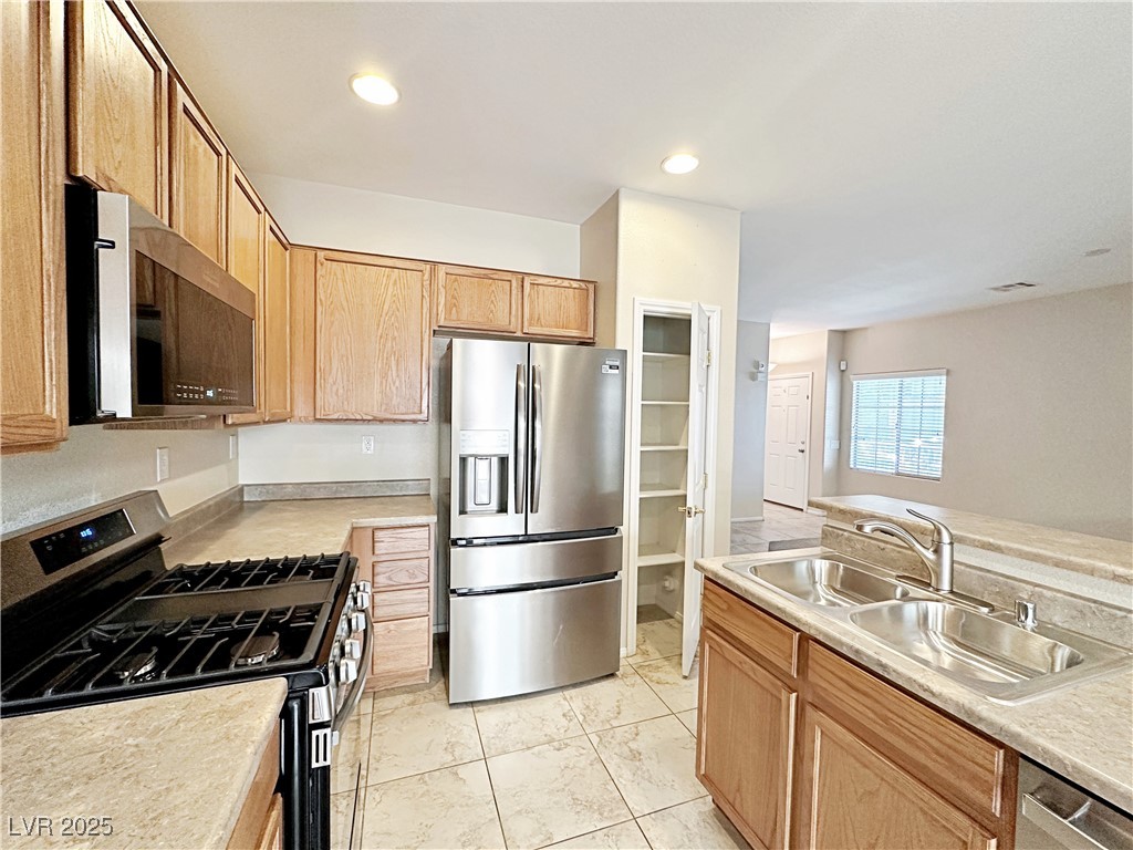 9620 Sharp Horn Court Las Vegas, NV 89149 - Photo 15 of 40 Kitchen with stainless steel appliances, light countertops, recessed lighting, light brown cabinets, and light tile patterned flooring
