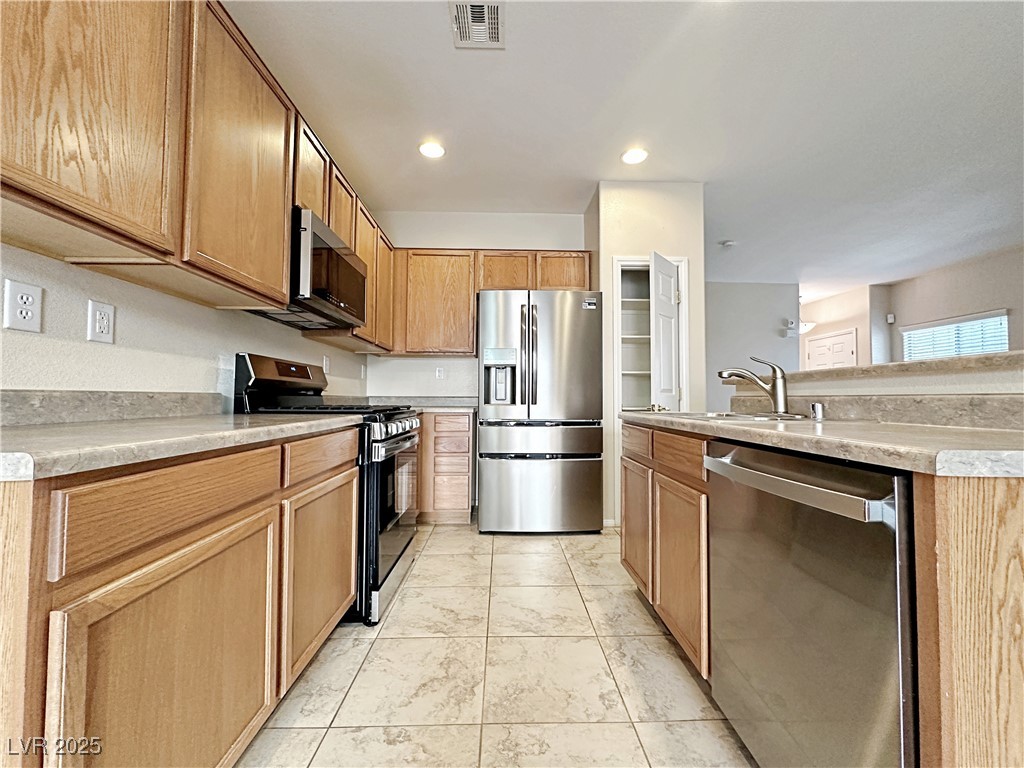 9620 Sharp Horn Court Las Vegas, NV 89149 - Photo 16 of 40 Kitchen featuring appliances with stainless steel finishes, light countertops, recessed lighting, an island with sink, and light tile patterned floors