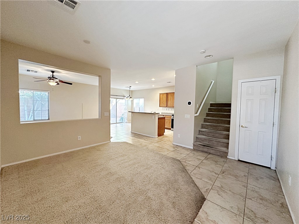 9620 Sharp Horn Court Las Vegas, NV 89149 - Photo 6 of 40 Unfurnished living room with light tile patterned floors, light carpet, stairs, recessed lighting, and a ceiling fan