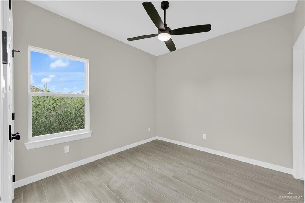 905 Crestview Street, Unit 2 Weslaco, TX 78596 - Photo 11 of 12 wooden floor in an empty room with a window