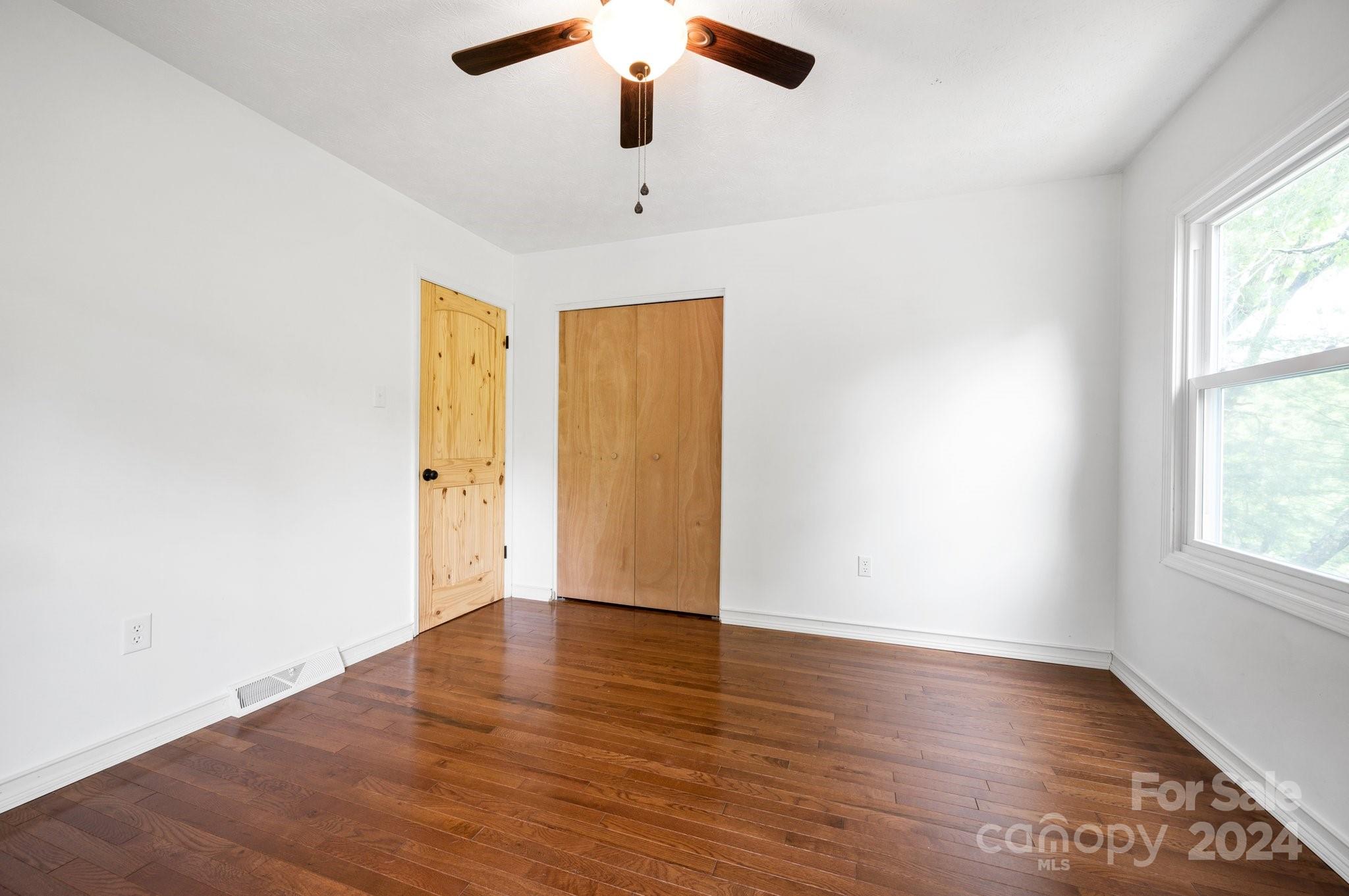 12 South Ridge Place Arden, NC 28704 - Photo 20 of 41 an empty room with wooden floor chandelier fan and windows