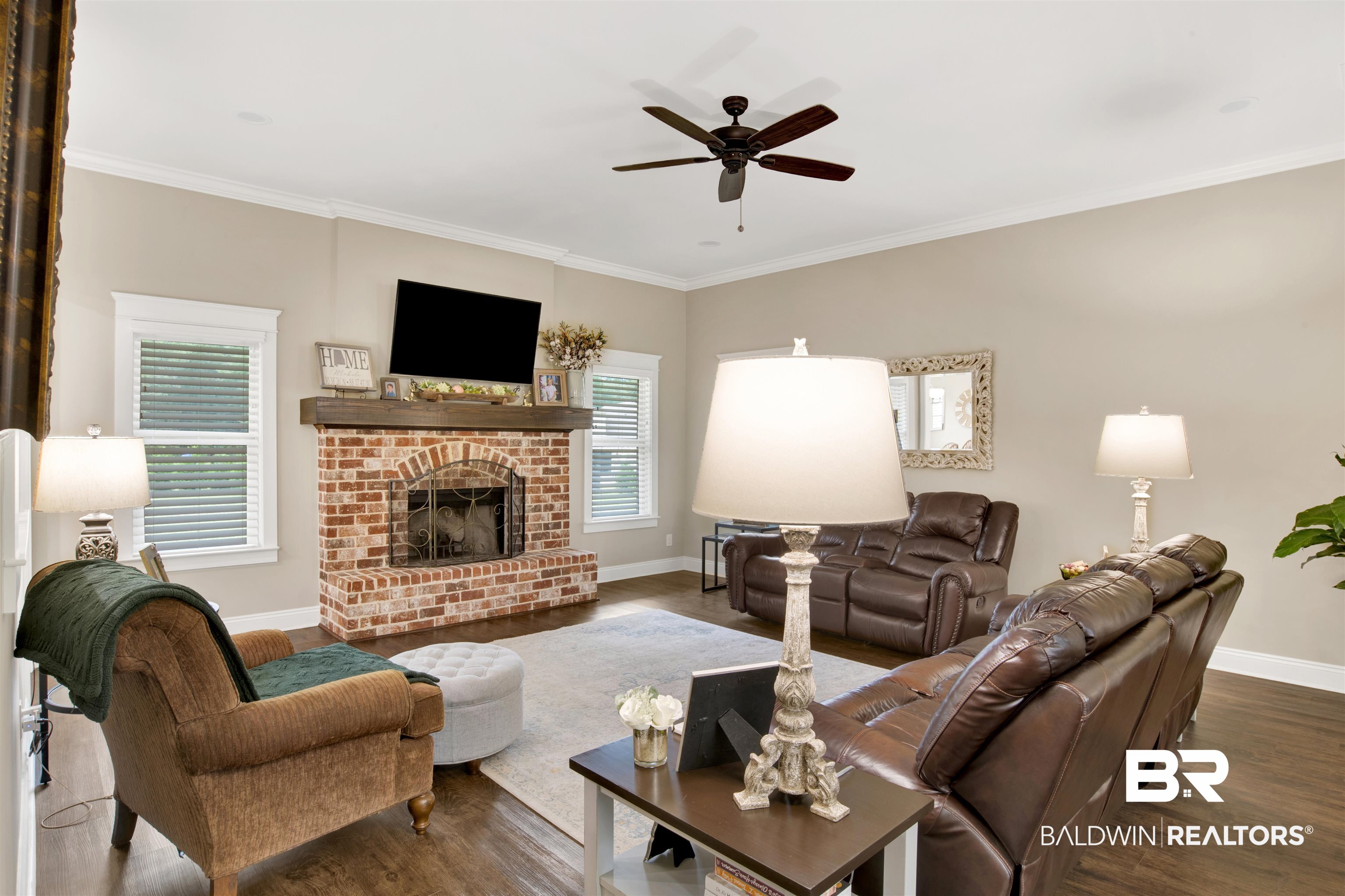2440 Johnson Road West Mobile, AL 36695 - Photo 22 of 40 Living room featuring a brick fireplace, ceiling fan, dark wood-type flooring, and ornamental molding