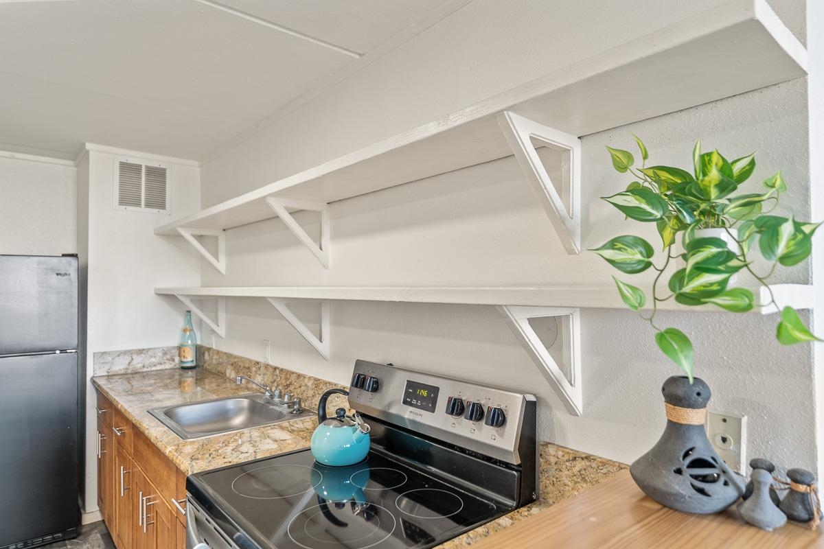 111 Kahului Beach Road, Unit A104 Kahului, HI 96732 - Photo 11 of 38 a kitchen with a stove and a white refrigerator