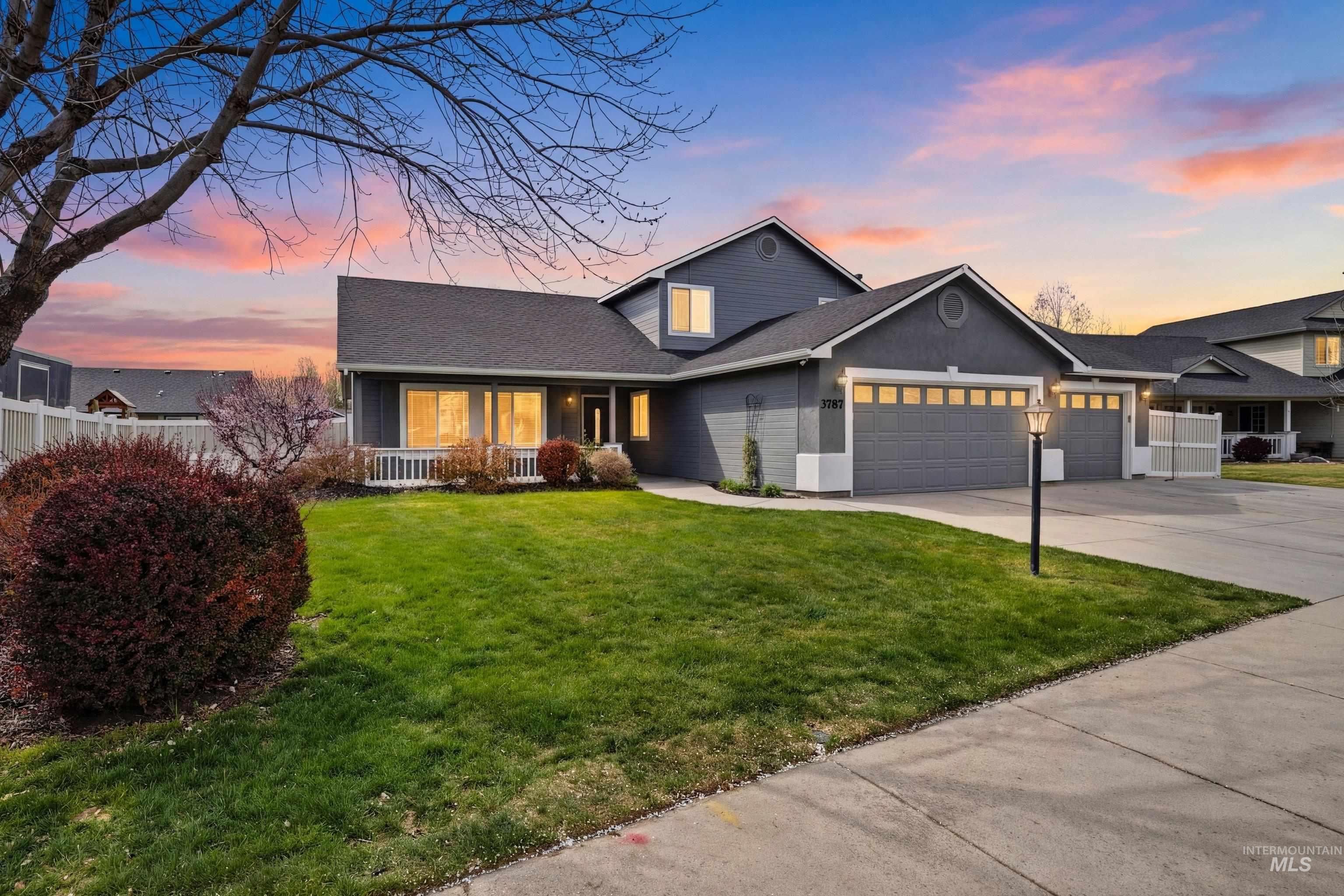 Traditional-style home featuring an attached garage, driveway, covered porch, and a shingled roof