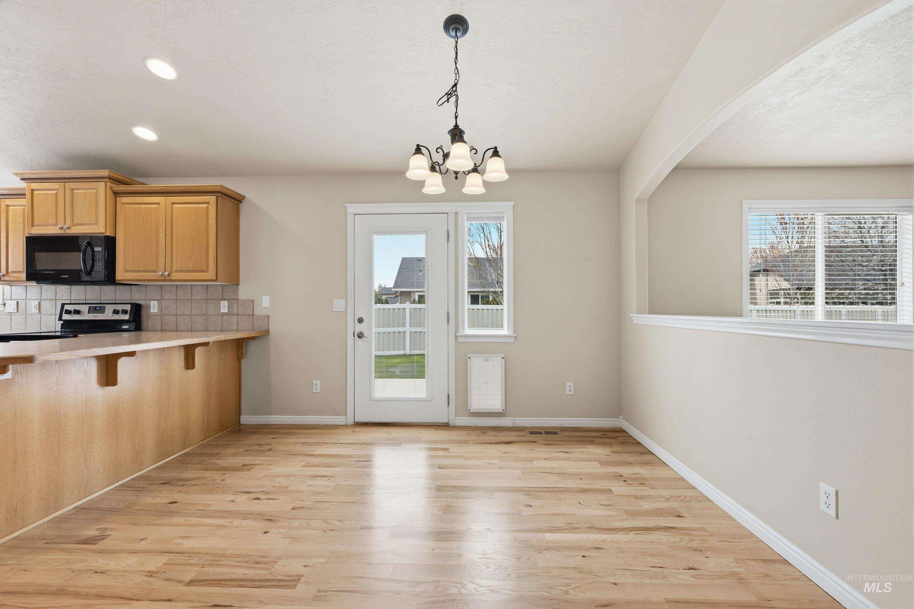 3787 North Alexis Way Meridian, ID 83646 - Photo 12 of 50 Kitchen featuring light countertops, a kitchen breakfast bar, light wood-style flooring, and backsplash
