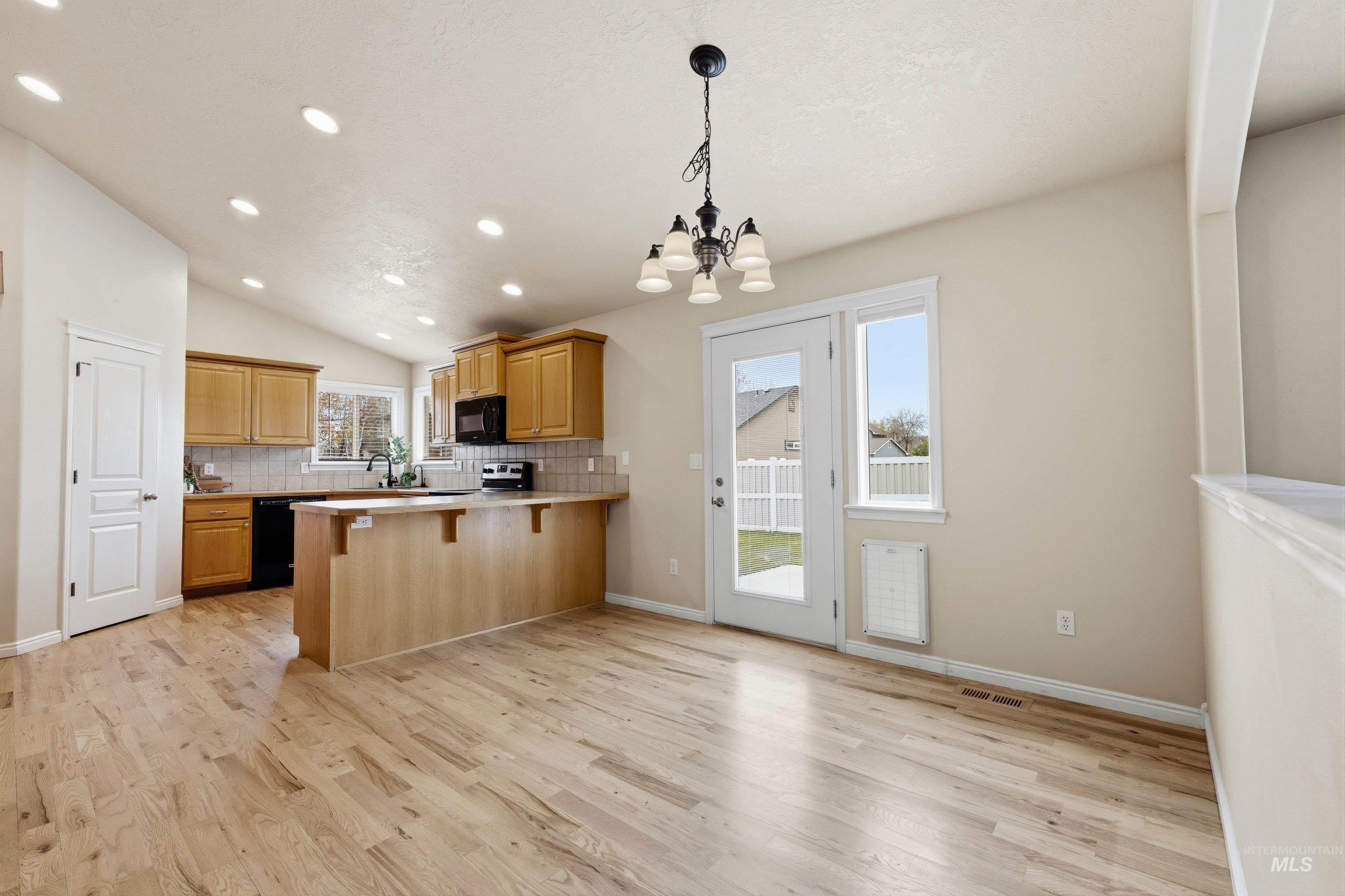 3787 North Alexis Way Meridian, ID 83646 - Photo 13 of 50 Kitchen with a breakfast bar, a peninsula, light countertops, a chandelier, and light wood-style floors