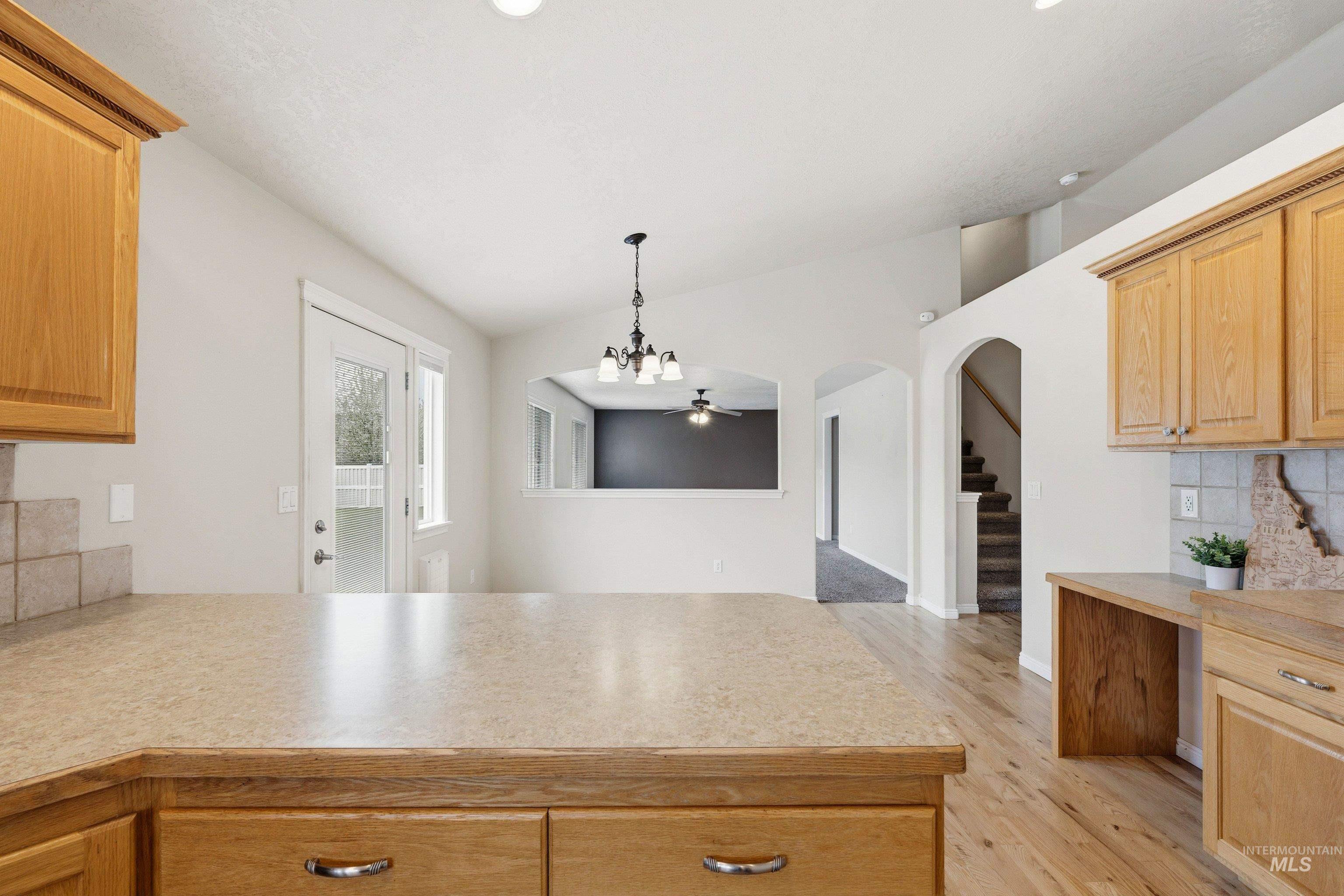 3787 North Alexis Way Meridian, ID 83646 - Photo 14 of 50 Kitchen featuring tasteful backsplash, light countertops, light wood finish cabinetry, a peninsula, and vaulted ceiling