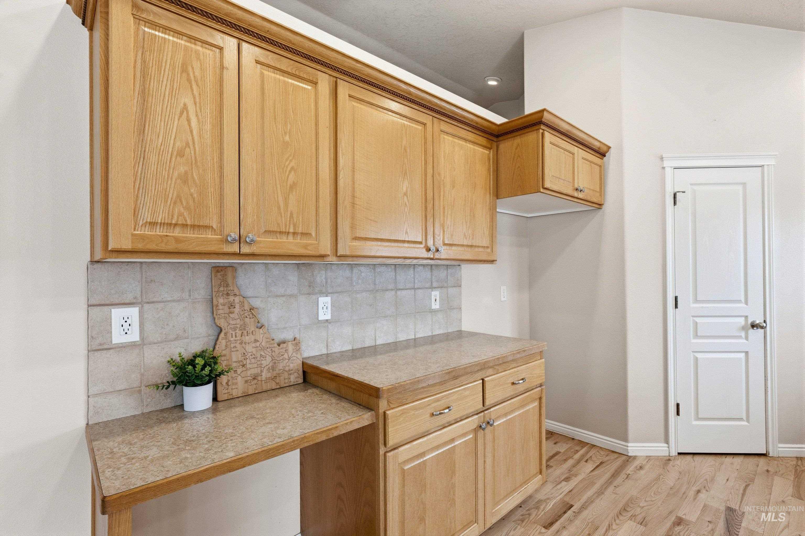 3787 North Alexis Way Meridian, ID 83646 - Photo 16 of 50 Kitchen featuring light countertops, decorative backsplash, light wood-style floors, and light wood finish cabinets