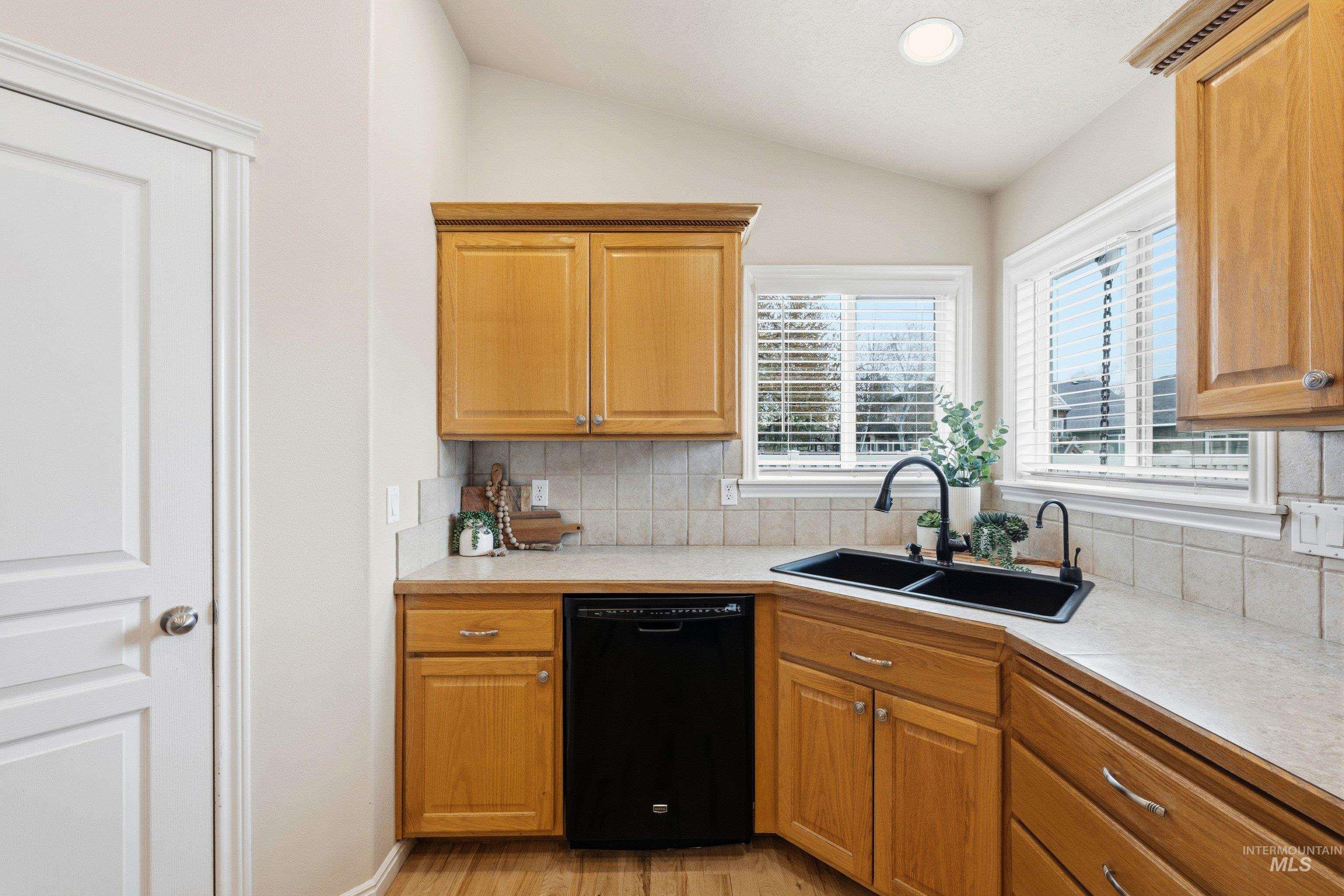 3787 North Alexis Way Meridian, ID 83646 - Photo 20 of 50 Kitchen with light countertops, dishwasher, lofted ceiling, light wood finished floors, and wood finish cabinets