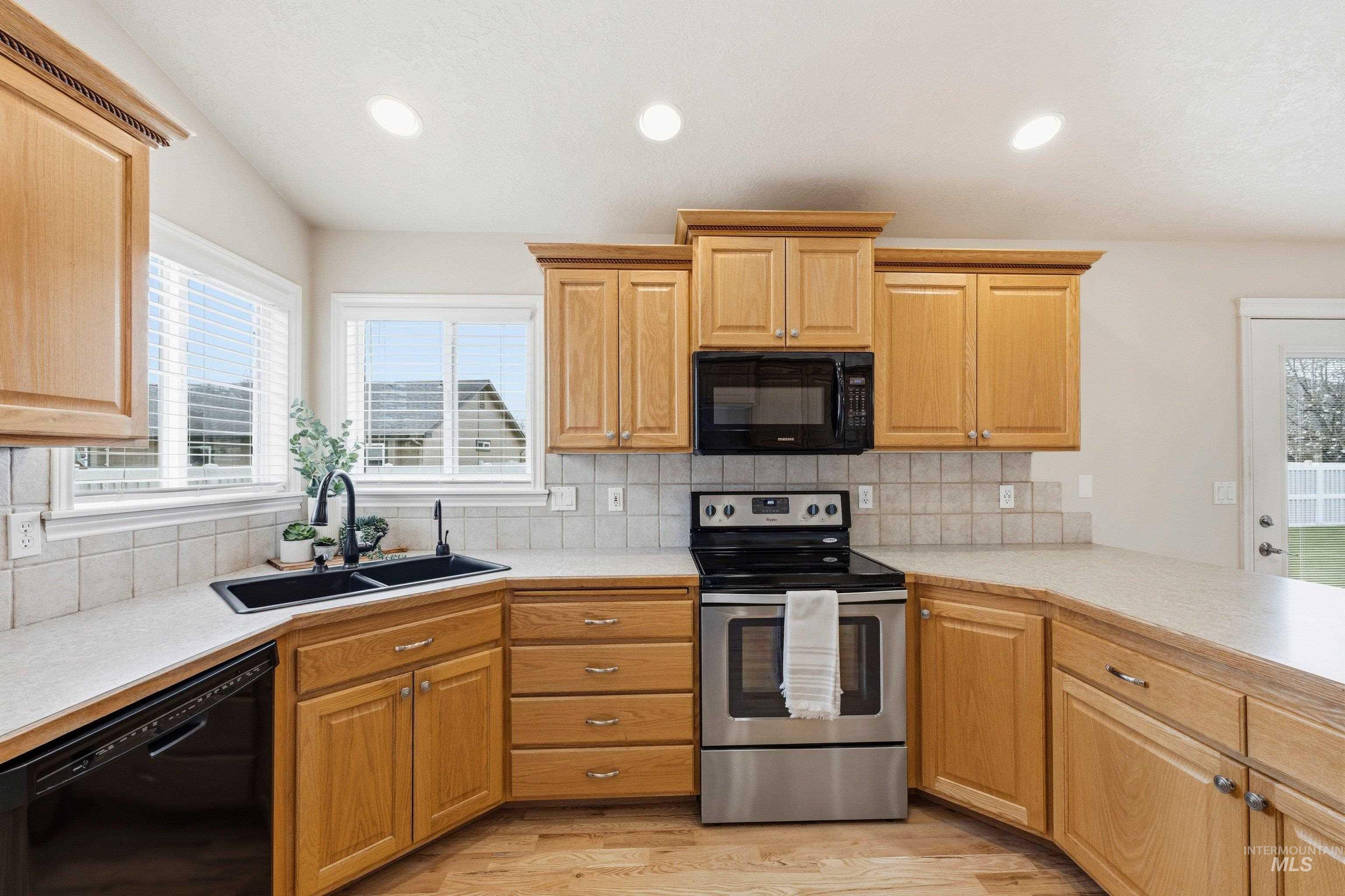 3787 North Alexis Way Meridian, ID 83646 - Photo 21 of 50 Kitchen with black appliances, light countertops, light wood-style floors, recessed lighting, and tasteful backsplash