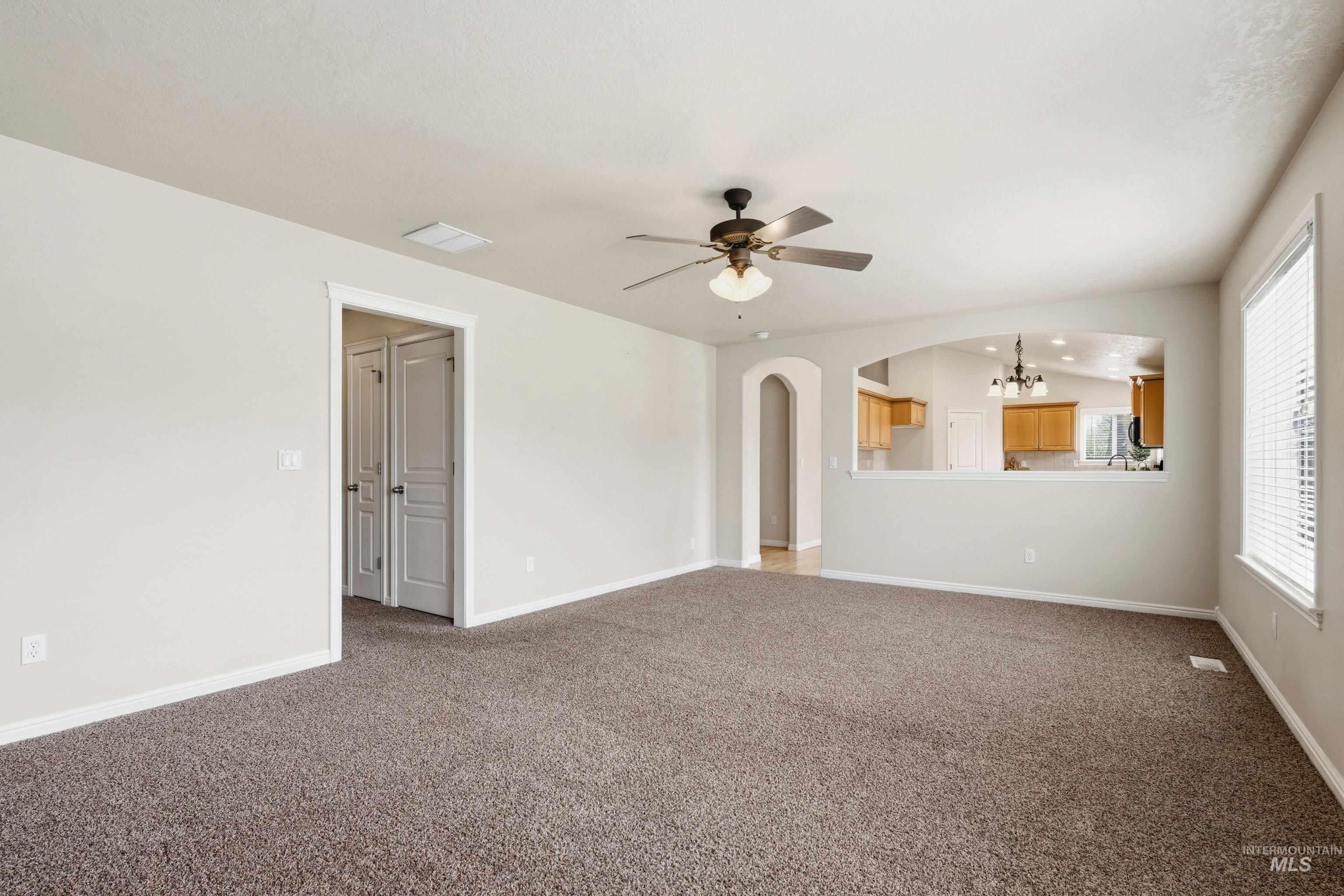3787 North Alexis Way Meridian, ID 83646 - Photo 25 of 50 Unfurnished living room with arched walkways, carpet, a ceiling fan, and suspended lighting