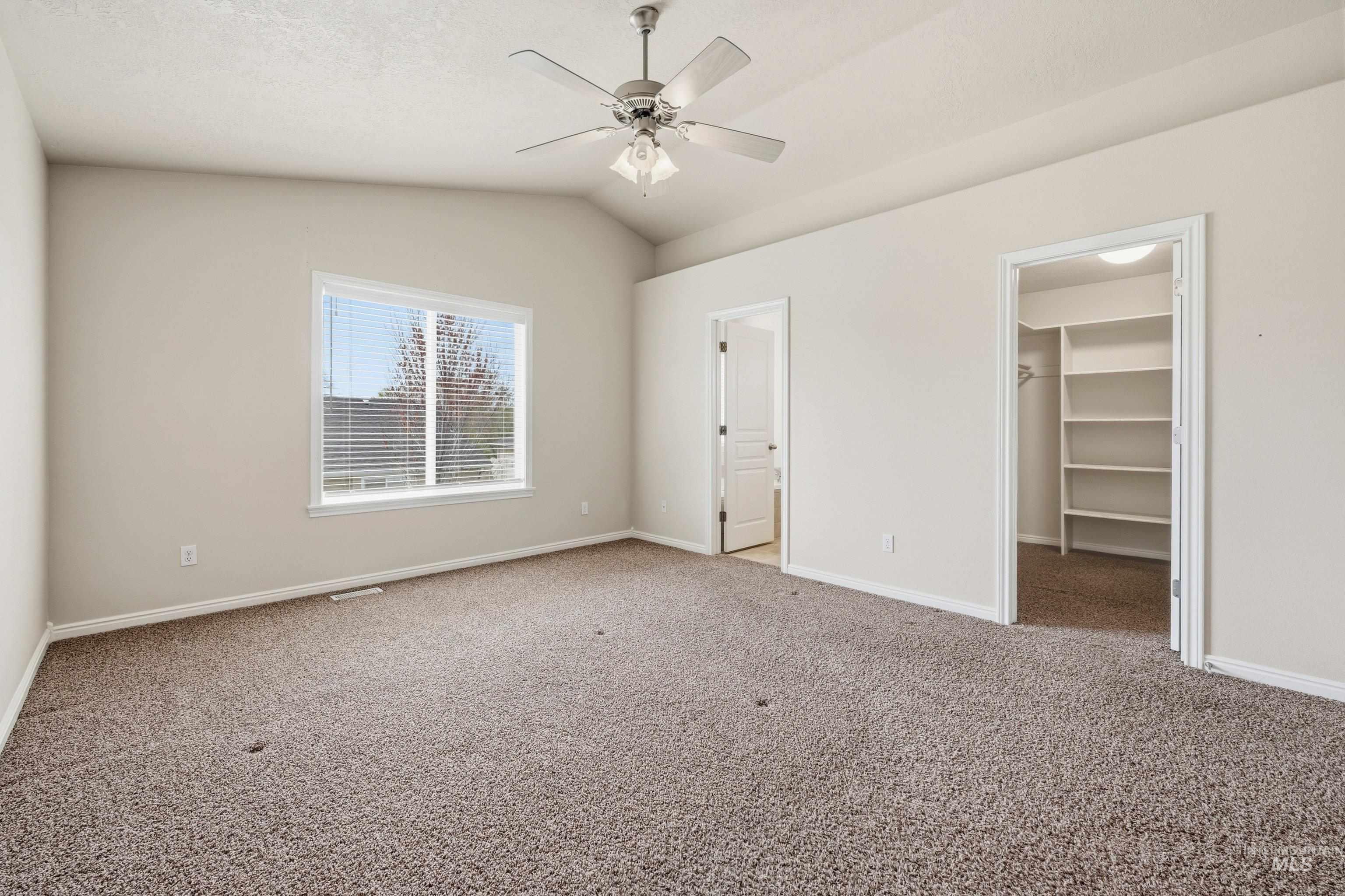 3787 North Alexis Way Meridian, ID 83646 - Photo 30 of 50 Unfurnished bedroom with lofted ceiling, carpet floors, a walk in closet, and a ceiling fan