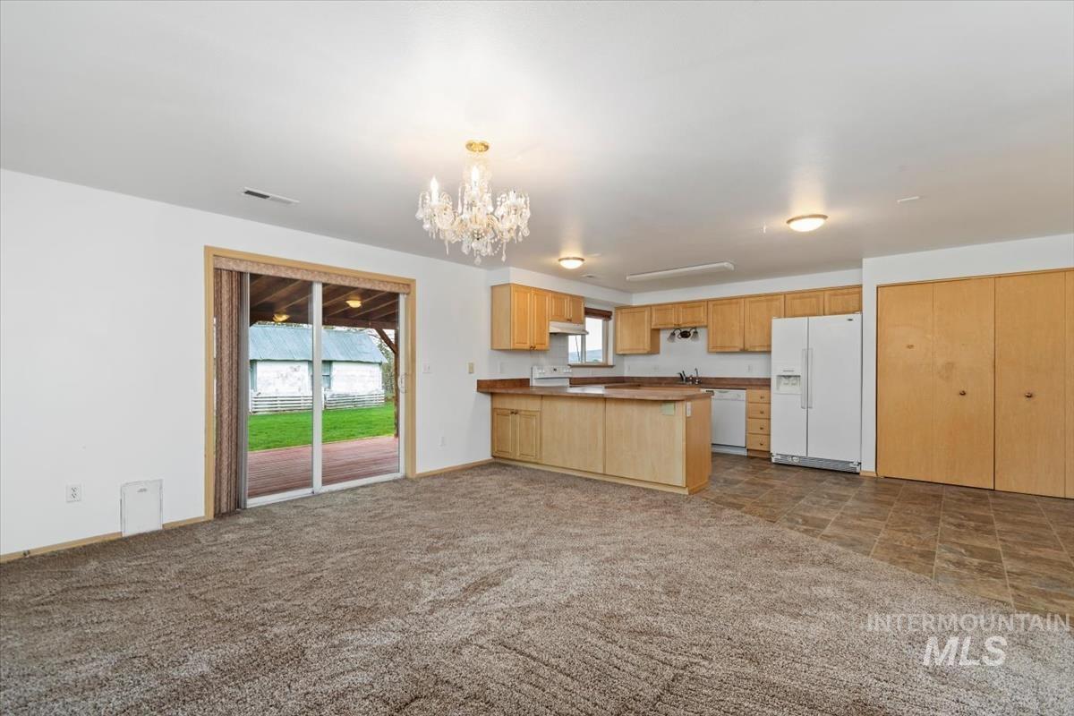 1051 Haas Road Weiser, ID 83672 - Photo 42 of 44 Kitchen with white appliances, a peninsula, a chandelier, open floor plan, and light wood finish cabinets