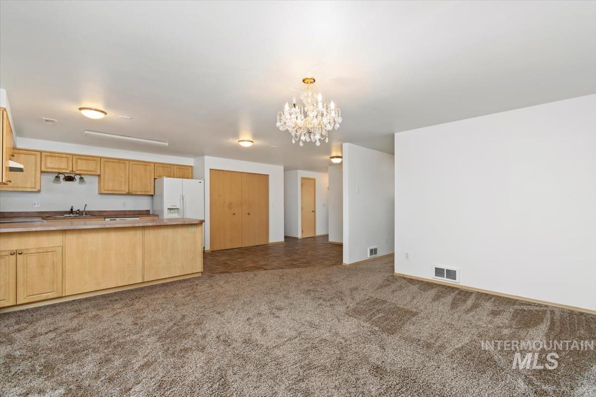 1051 Haas Road Weiser, ID 83672 - Photo 43 of 44 Kitchen featuring a chandelier, white refrigerator with ice dispenser, open floor plan, a peninsula, and light wood finish cabinetry