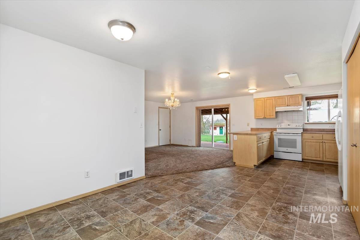 1051 Haas Road Weiser, ID 83672 - Photo 20 of 44 Kitchen with light wood finish cabinetry, healthy amount of natural light, dark stone finish flooring, and white appliances