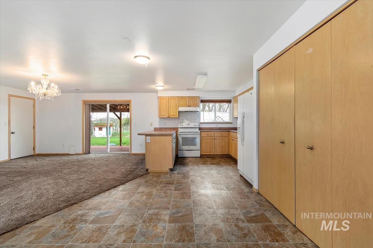 1051 Haas Road Weiser, ID 83672 - Photo 44 of 44 Kitchen featuring stone finish flooring, white appliances, light wood finish cabinets, open floor plan, and suspended lighting