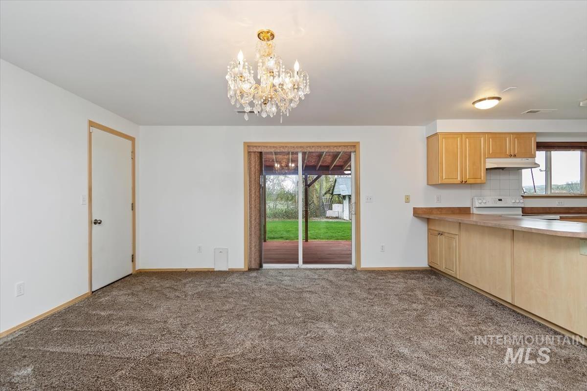 1051 Haas Road Weiser, ID 83672 - Photo 10 of 44 Kitchen featuring light wood finish cabinets, dark colored carpet, hanging lights, light countertops, and white range with electric cooktop