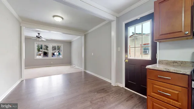 an empty room with wooden floor cabinet and windows