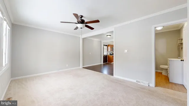 a view of a livingroom with a chandelier fan and wooden floor