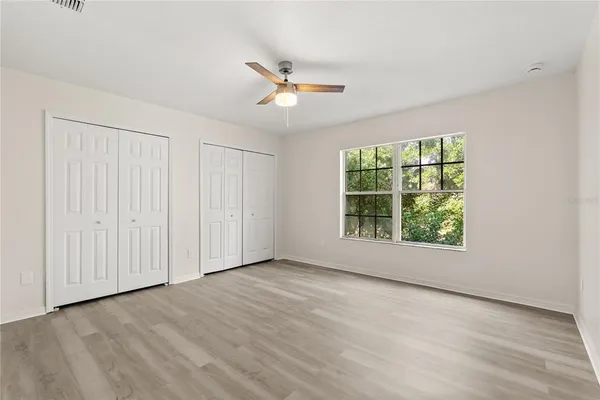 an empty room with wooden floor cabinet and windows