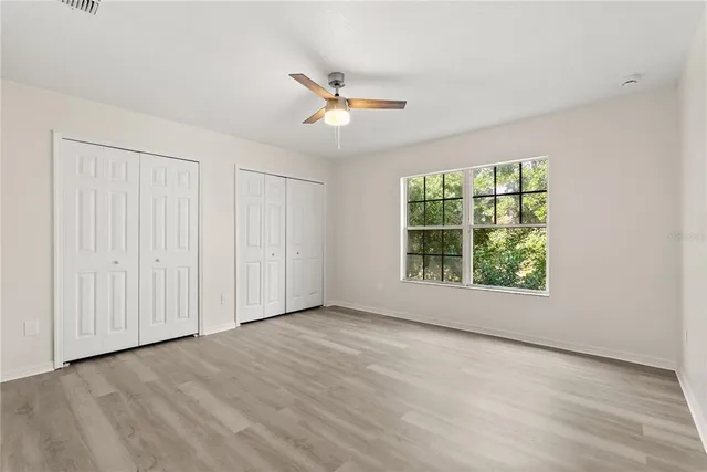 an empty room with wooden floor cabinet and windows