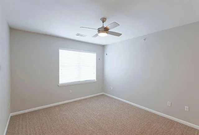 an empty room with closet and a ceiling fan