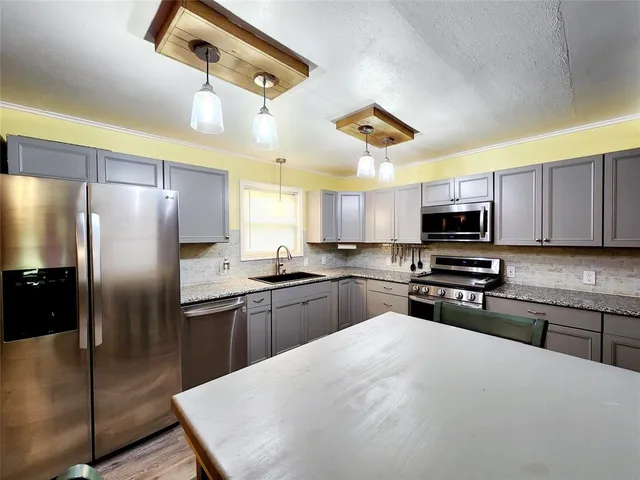 a kitchen with stainless steel appliances granite countertop a refrigerator a stove microwave and sink