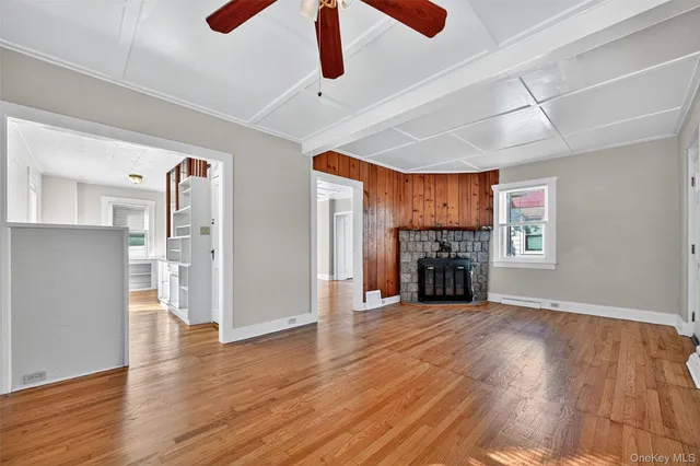a view of a livingroom with a fireplace wooden floor cabinet and a ceiling fan