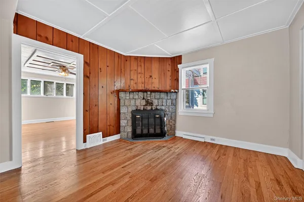 a view of an empty room with a window and wooden floor