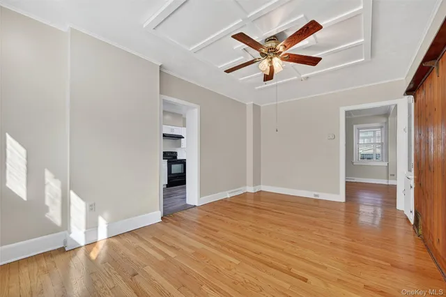a view of empty room with wooden floor and ceiling fan