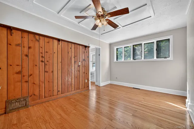 an empty room with wooden floor fan and windows
